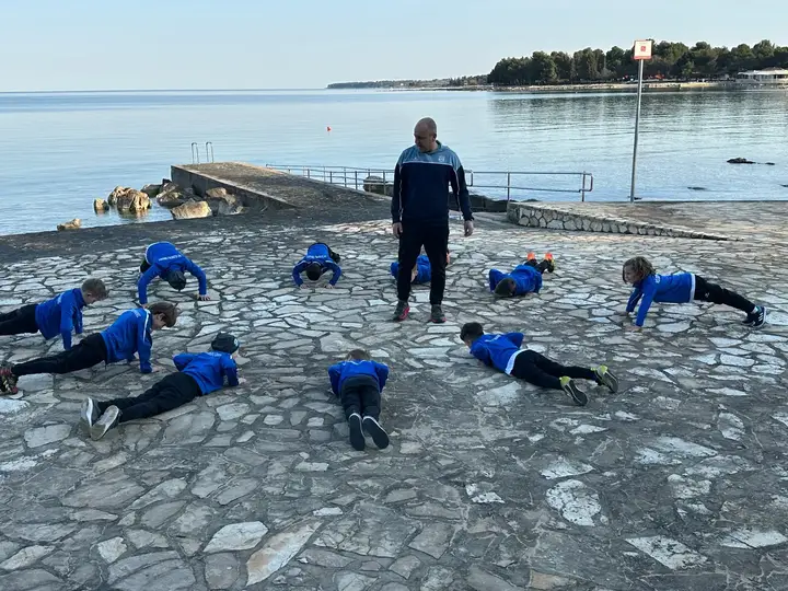 Trener vodi vadbo mladih igralcev ob morju